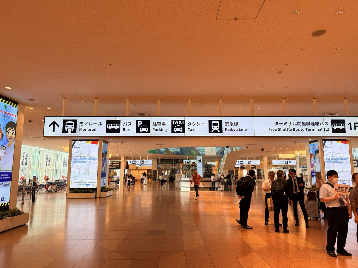 The overhead directional sign at Haneda Terminal 3 arrivals, showing five options: Monorail, Bus, Parking, Taxi, and Keikyu Line
